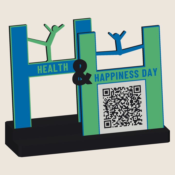 3D-printed Health and Happiness Day booth sign: two large H letters on a plinth with gymnast figures leaping through them and a QR code in the green H