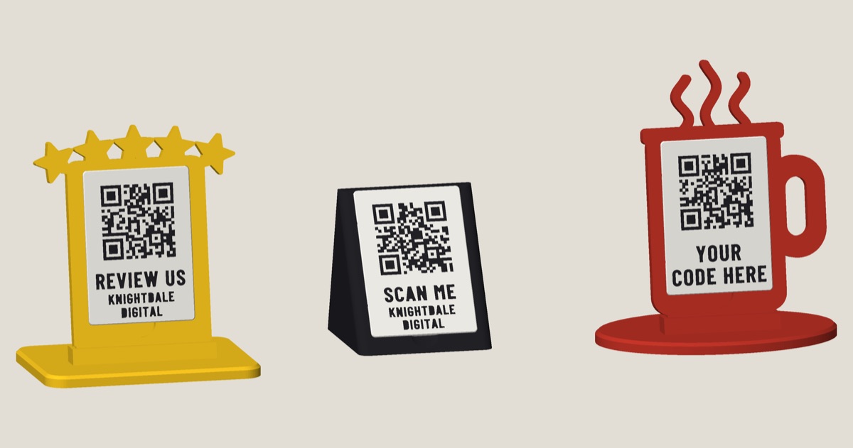 Three ready-made 3D-printed QR signs: a yellow five-stars stand reading REVIEW US, a black wedge reading SCAN ME and a red coffee cup reading YOUR CODE HERE